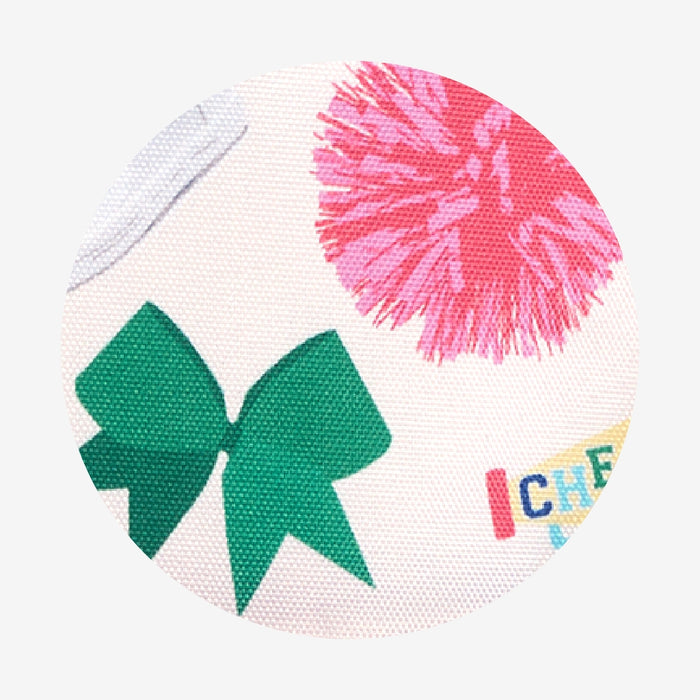 Close-up of fabric with a green bow and pink pom-pom on a white background.
