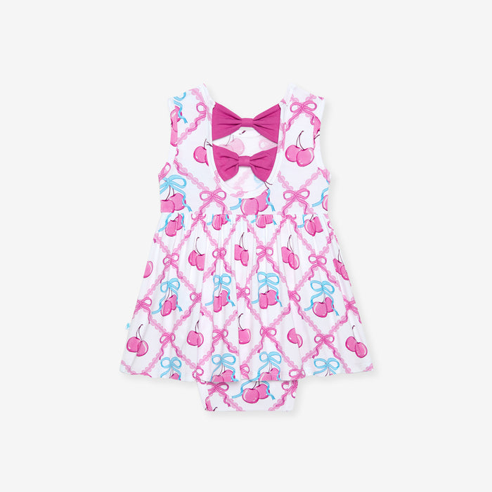 Children's dress with pink and blue bow pattern on a white background
