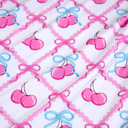 Pattern of pink cherries and blue bows on a white background