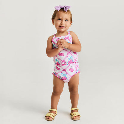 Child wearing a pink bummie set with cherry and bow design on a white background