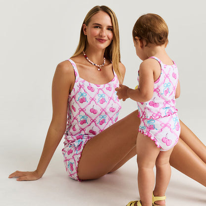 Woman and child wearing matching pink sets with cherries and bow patterns on a white background