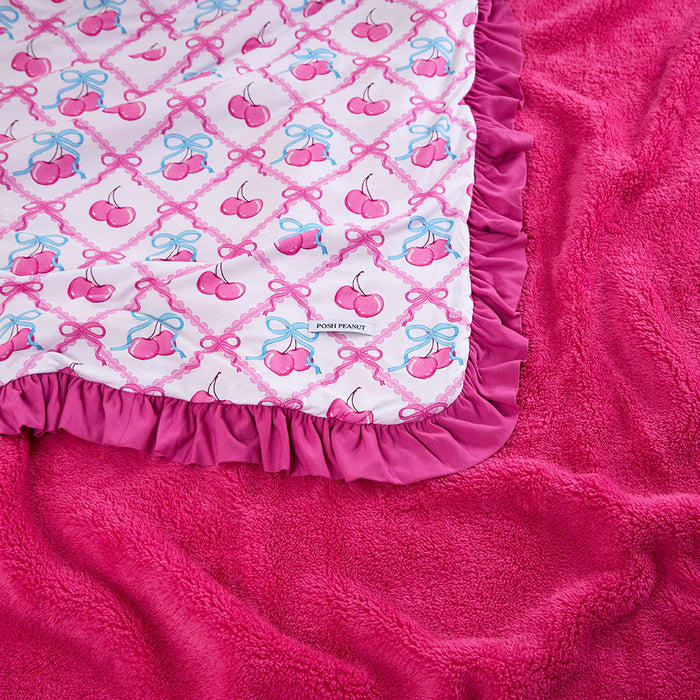 Pink blanket with cherry and bow pattern on a matching pink background