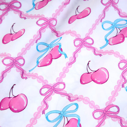Pattern of pink cherries and blue bows on a white background