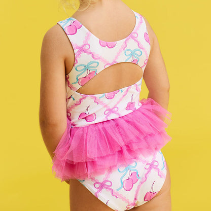 Child wearing a colorful swimsuit with a tutu on a yellow background