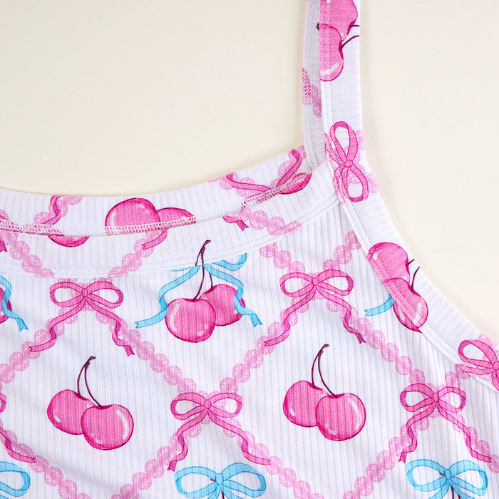 White top with pink cherries and blue bows on a light beige background