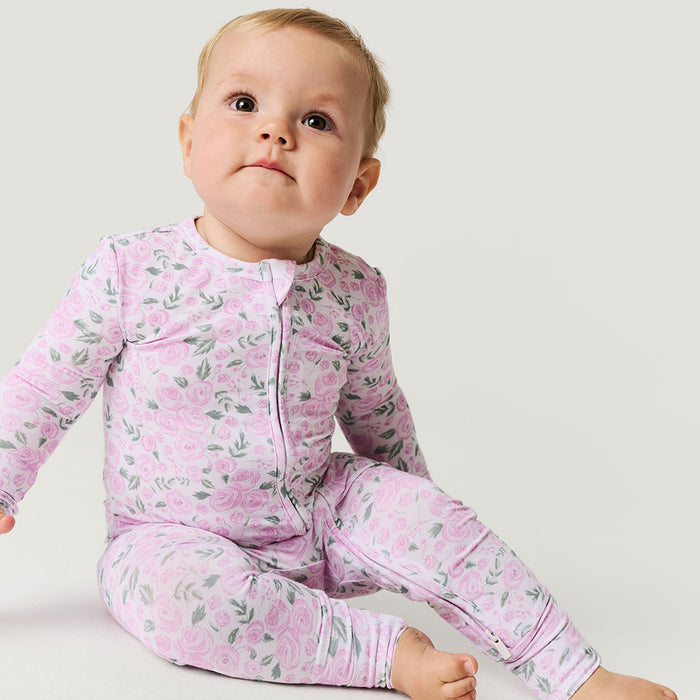 Baby wearing a pink floral one piece on a white background