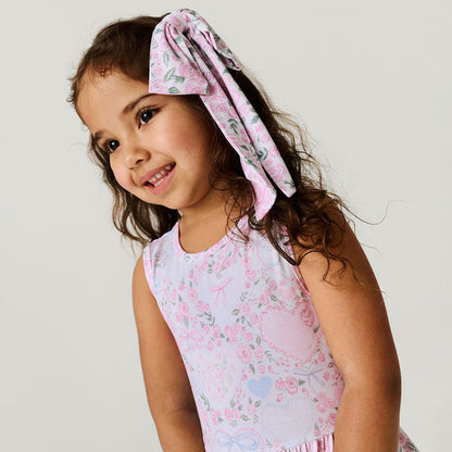 Close up detail image of child with hair bow and floral printed dress.