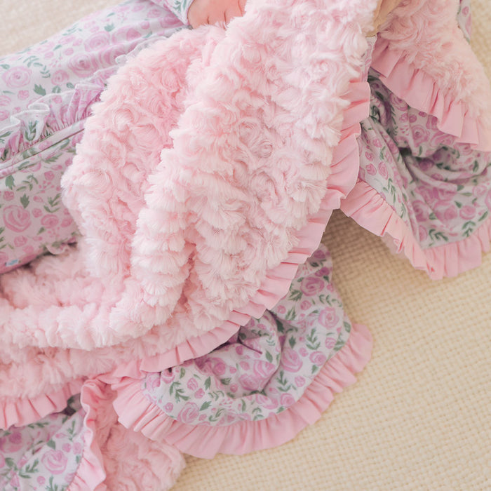 Pink ruffled blanket with floral pattern on a beige background