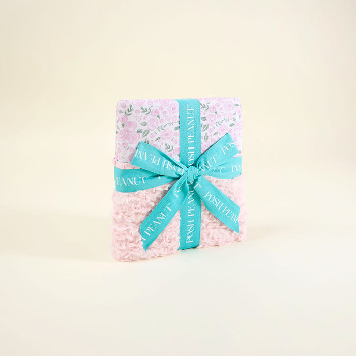 pink floral pattern blanket wrapped in a blue ribbon on a beige background