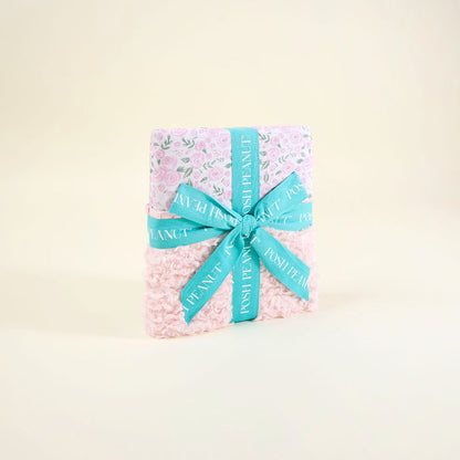 pink floral pattern blanket wrapped in a blue ribbon on a beige background
