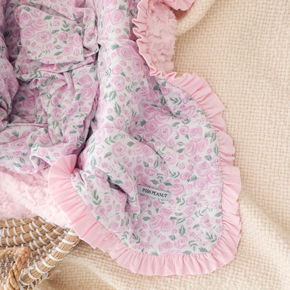 Pink floral baby blanket with ruffles on a beige surface, featuring 'Posh Peanut' branding.