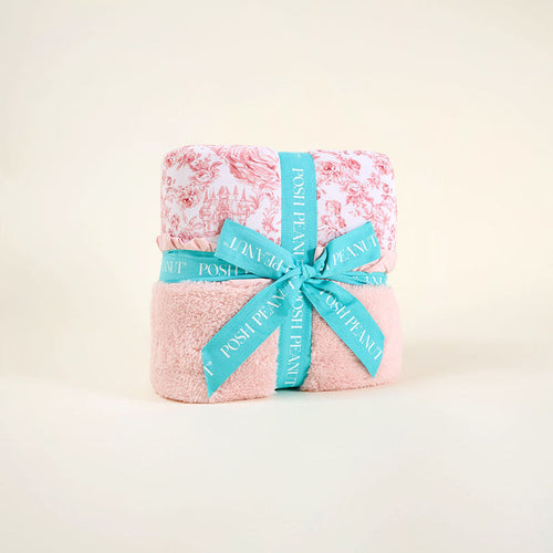 Pink floral blanket wrapped with a blue ribbon on a beige background