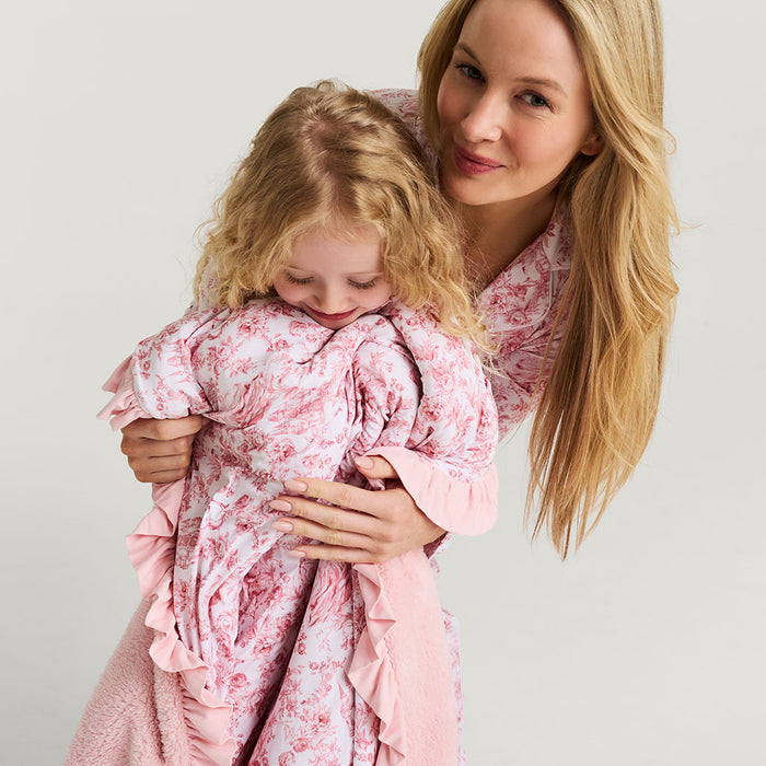 Woman and child in matching pink floral pijamas against a plain background