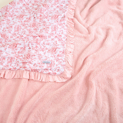 Pink floral blanket with ruffled edge on a pink textured fabric background