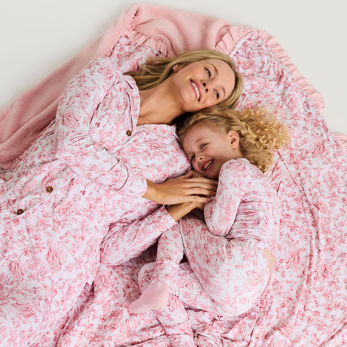 Woman and child lying on a pink floral blanket