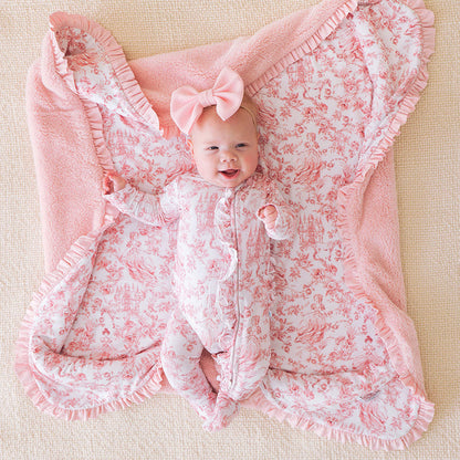 Baby wrapped in a pink floral blanket with a bow on a beige background