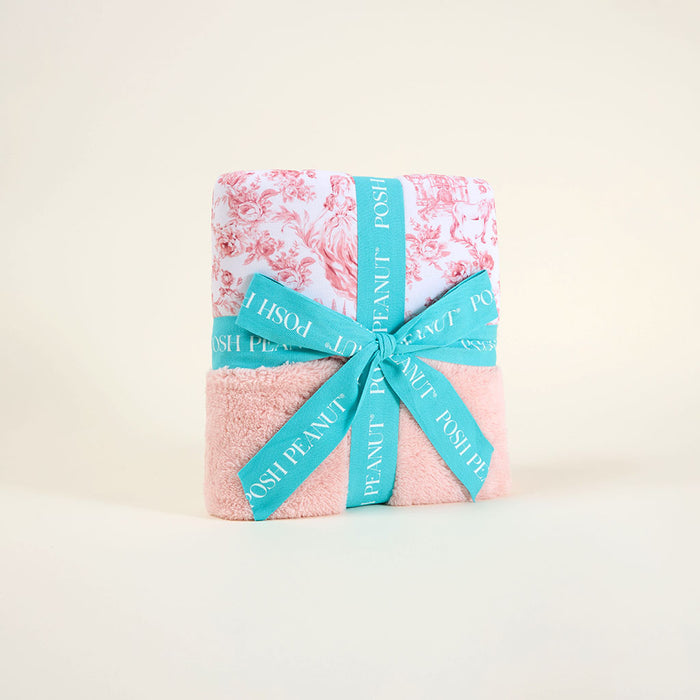 Pink floral blanket wrapped with a blue ribbon on a light background