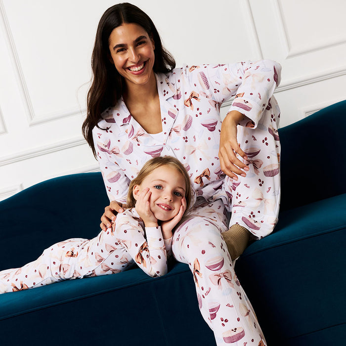 Woman and child sitting on a blue couch wearing matching pajamas with beans and bows pattern.