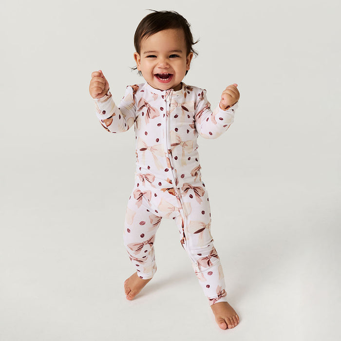 Child wearing a coffee beans and bows one piece on a plain background.