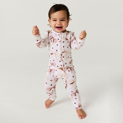 Child wearing a coffee beans and bows one piece on a plain background.