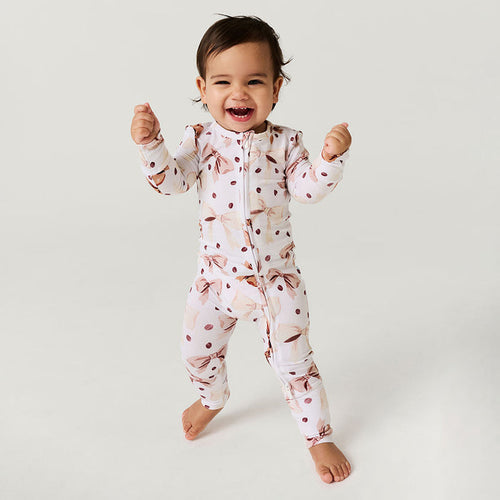 Child wearing a coffee beans and bows one piece on a plain background.