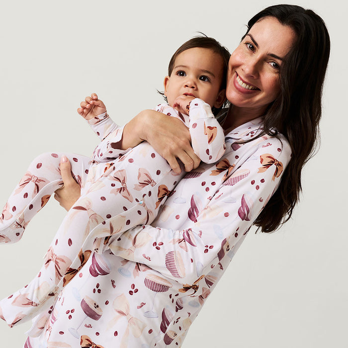 Woman and child wearing matching pajamas with a white background