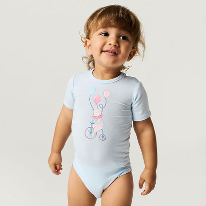 Child wearing a light blue bodysuit with a graphic design on a plain background