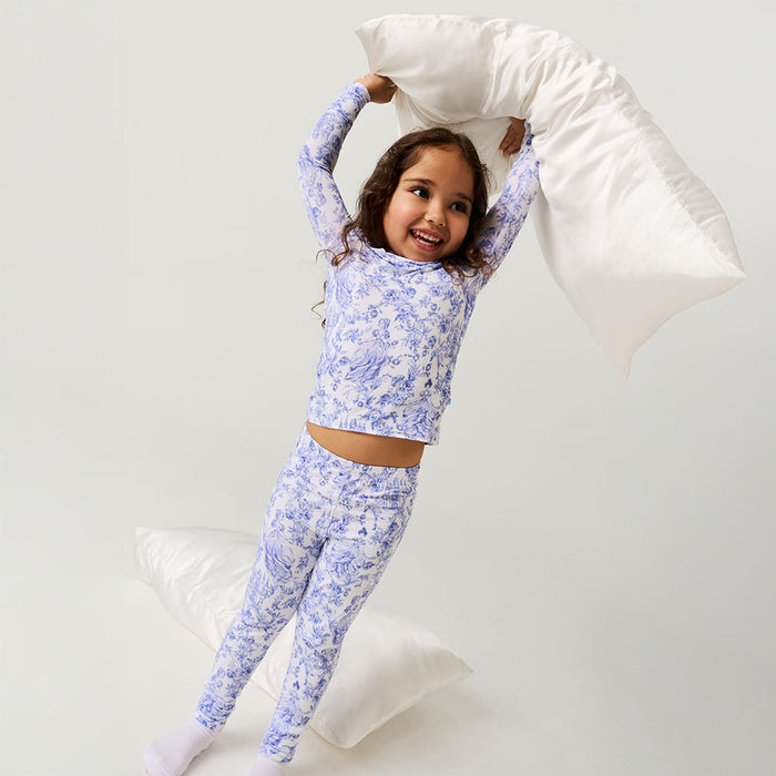 Child wearing blue floral pajamas holding a pillow against a white background