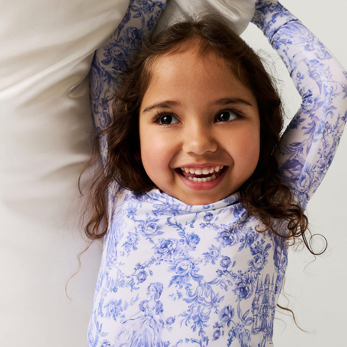 Young girl wearing a blue floral dress lying on a white surface