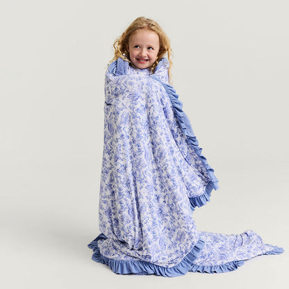 Child wrapped in a blue floral blanket on a plain background