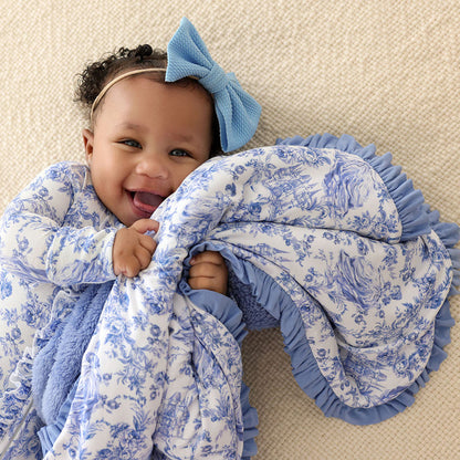 Baby wrapped in a blue and white patterned blanket with a large blue bow.