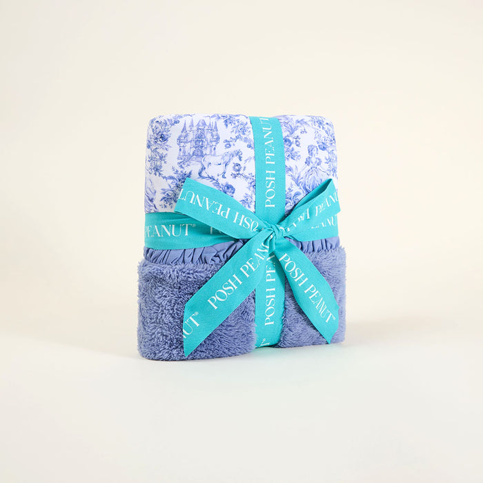 Folded blue blanket wrapped with a blue pattern and turquoise ribbon on a light beige background