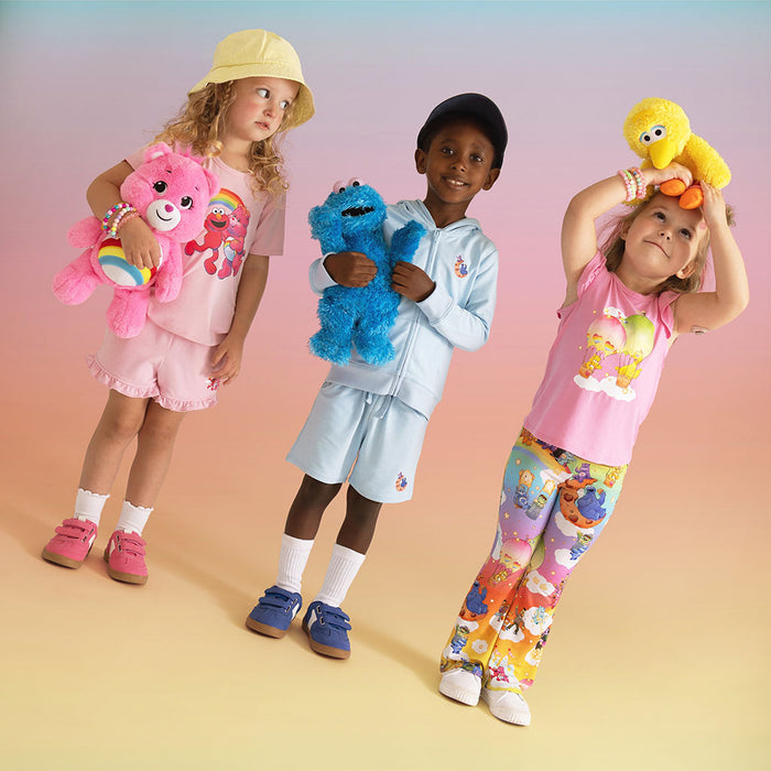 Three children holding plush toys against a gradient background