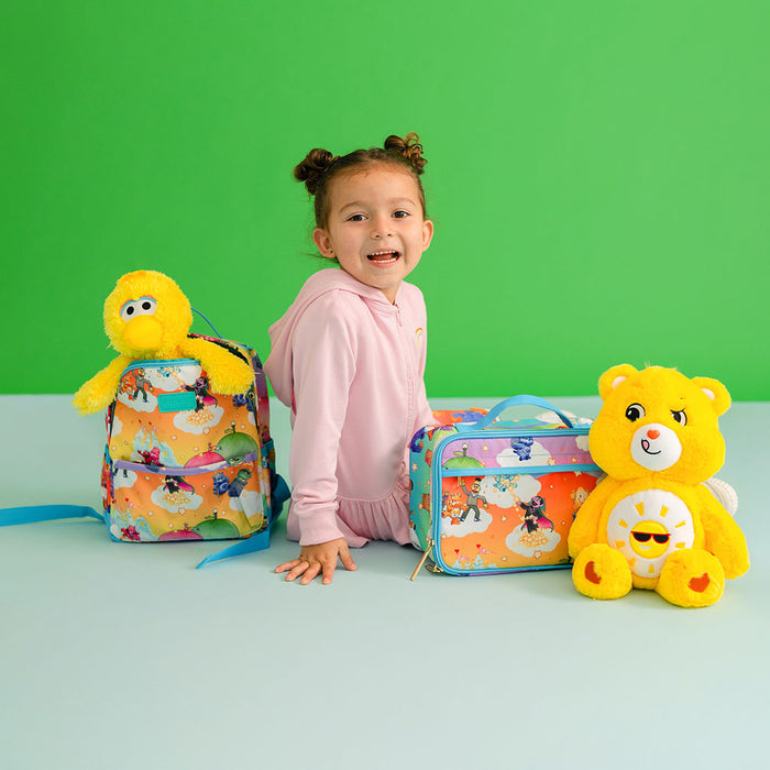 Child with colorful backpack and lunch bag on a green background