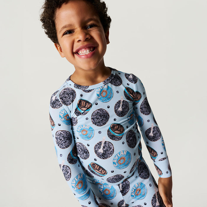 Child wearing a long-sleeve shirt with caviar pattern on a plain background