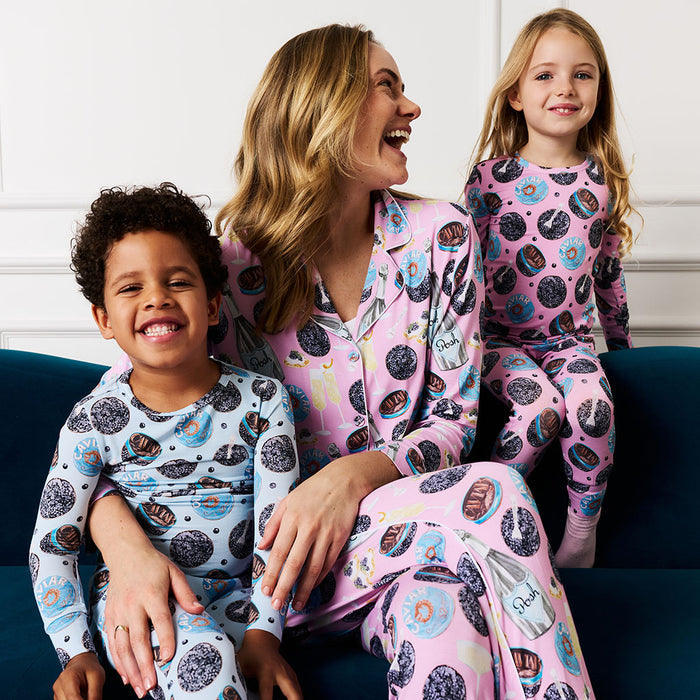 Family of three wearing matching pajamas with a pink and blue design on a blue couch.