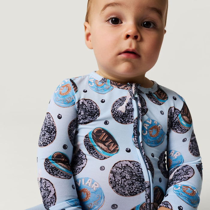 Baby wearing a onesie with caviar design on a plain background