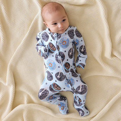 Baby wearing a patterned one piece lying on a beige blanket