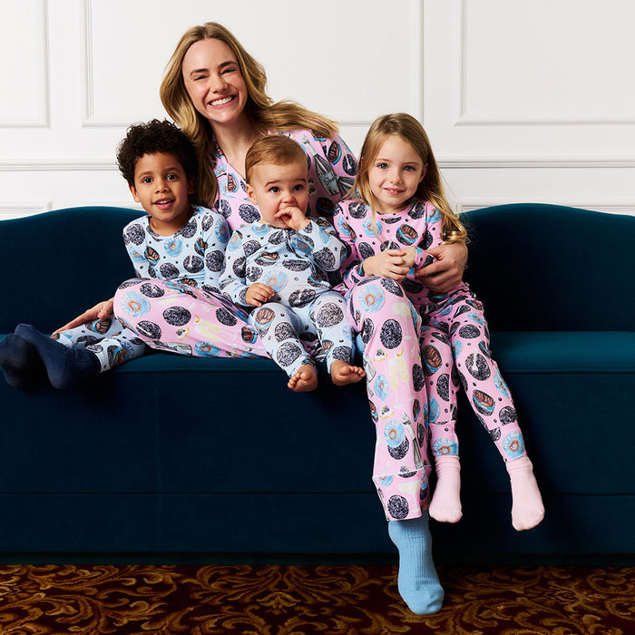 Woman with three children sitting on a blue couch wearing matching pajamas.
