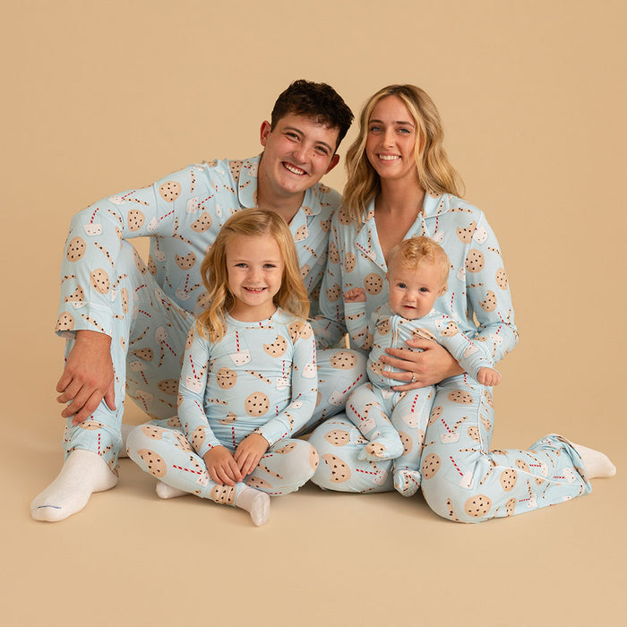 Family of four wearing matching pajamas with a cookie pattern on a beige background