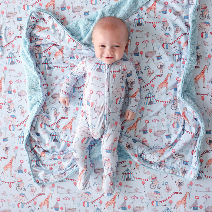 Baby in a patterned one piece with circus-themed design.
