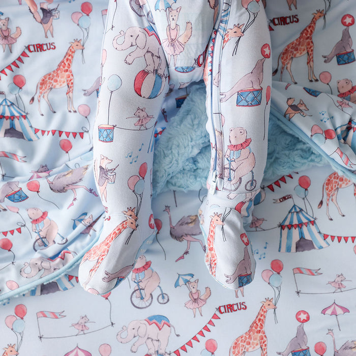 Children's one piece footie detail  with circus-themed design featuring animals and tents.
