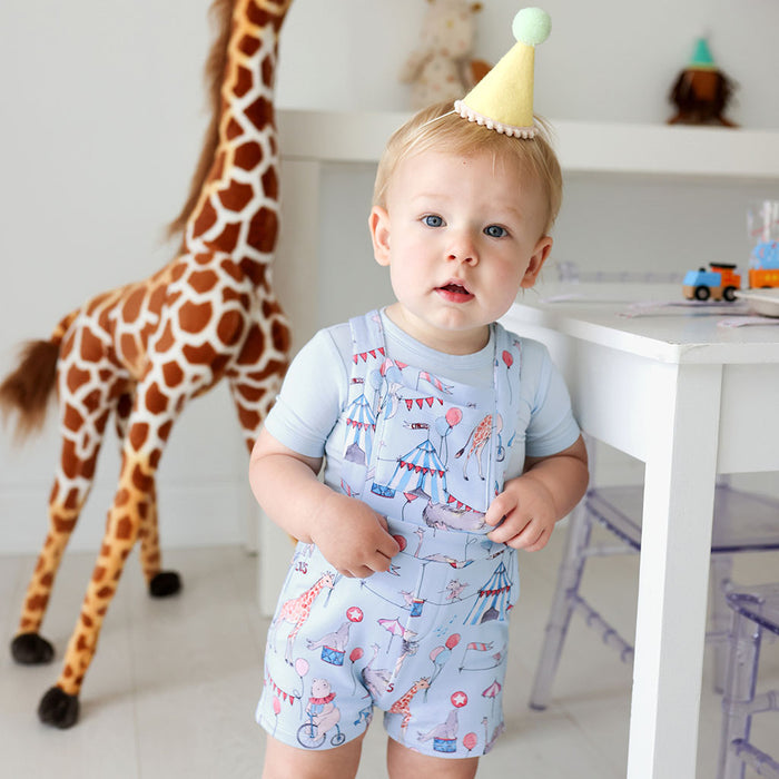 baby standing wearing french terry short overalls