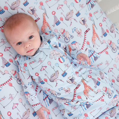 baby laying down in a circus printed sleeveless sleepbag
