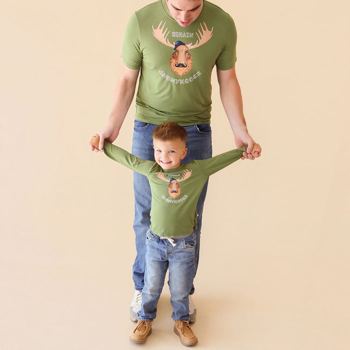 Father and child wearing matching green t-shirts with a moose graphic on a beige background