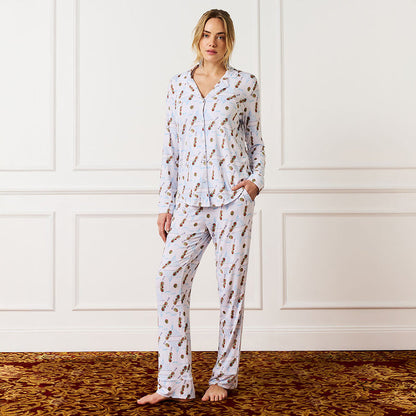 Woman wearing a patterned pajama set against a white paneled wall.