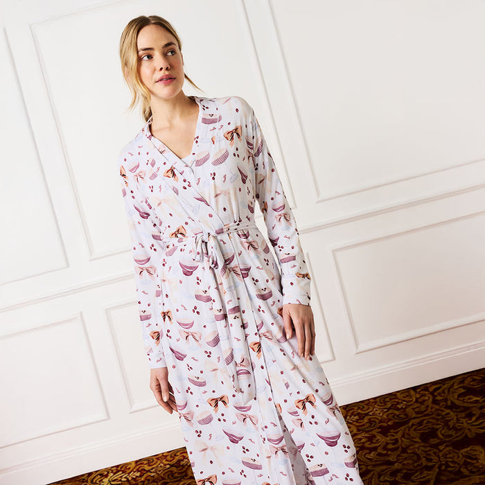 Woman wearing a espresso martini patterned robe against a white paneled wall.