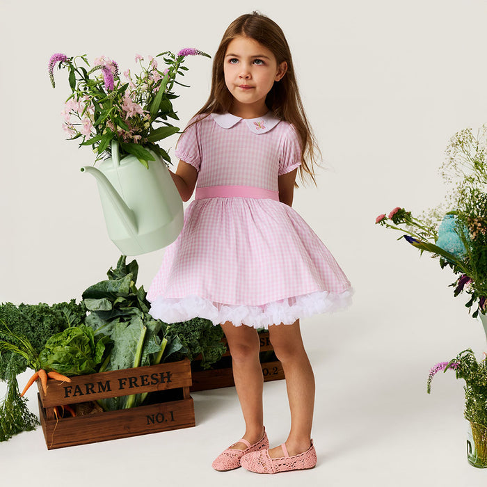Girl wearing bamboo viscose dress in pink gingham print with short sleeves and full skirt