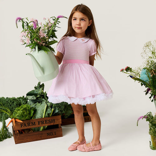Girl wearing bamboo viscose dress in pink gingham print with short sleeves and full skirt