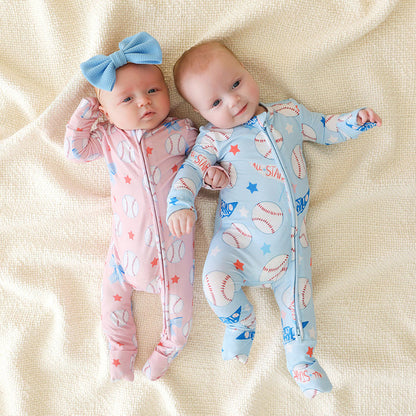 Two babies wearing colorful onesies on a beige blanket